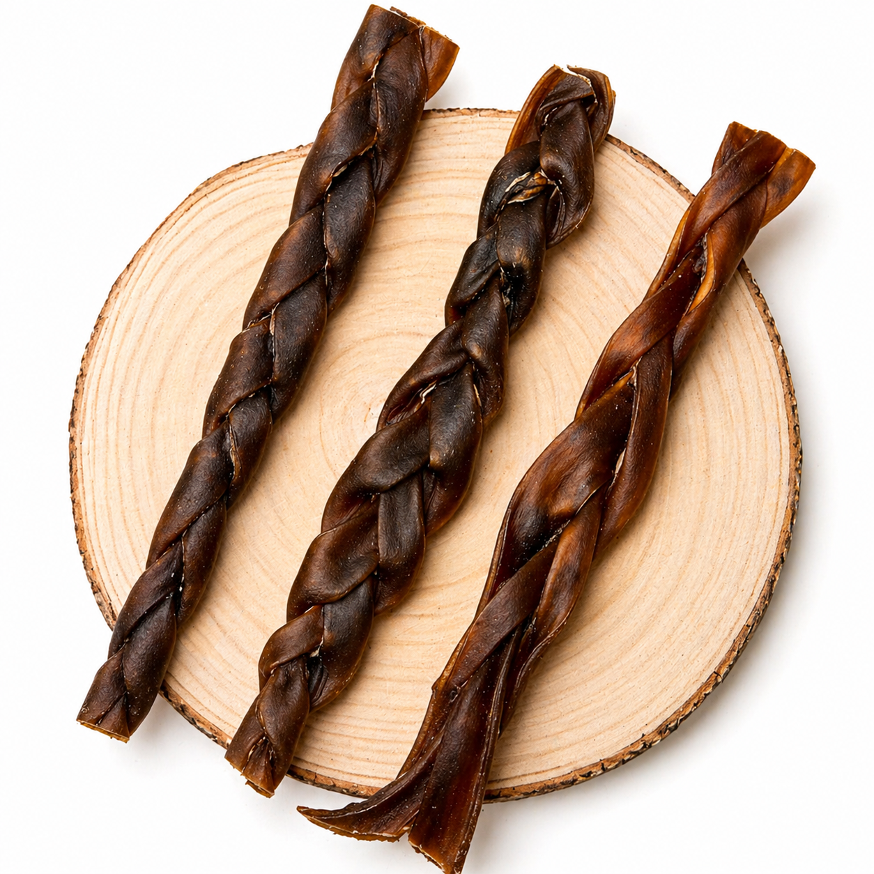 Braided camel dog chew sticks arranged on a natural wood slice, showcasing durable, twisted texture and rich brown colour natural long lasting dog treat for dental health and chewing.