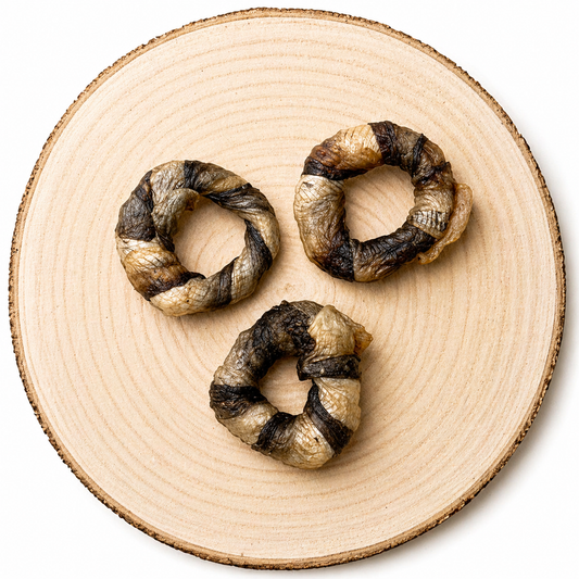 Three braided fish skin chew rings (“fish donuts”) arranged in a triangular layout on a natural wood slice, showing a mix of light and dark textures against a clean, neutral background.