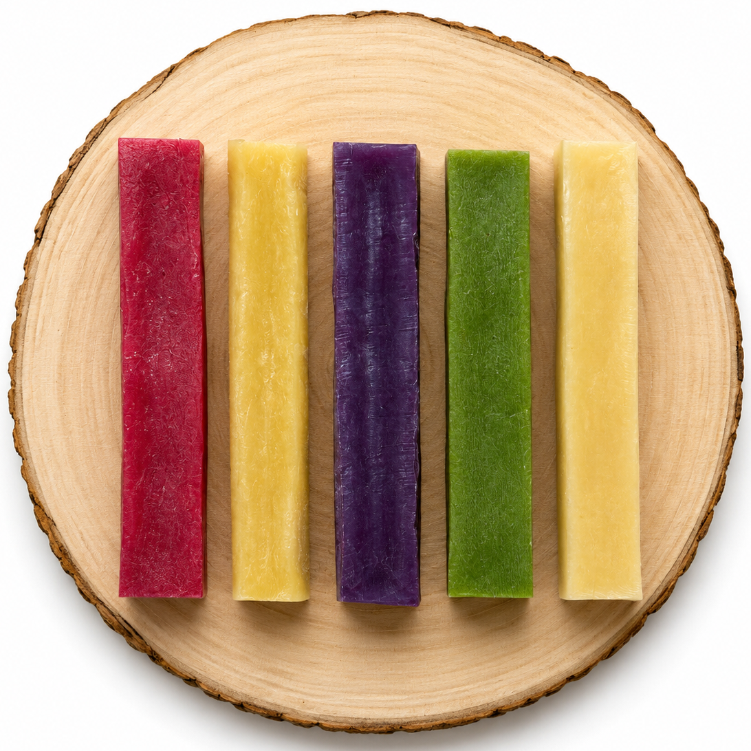 Large yak chews in flavours raspberry, original, blueberry, mint and chamomile on a wooden log.